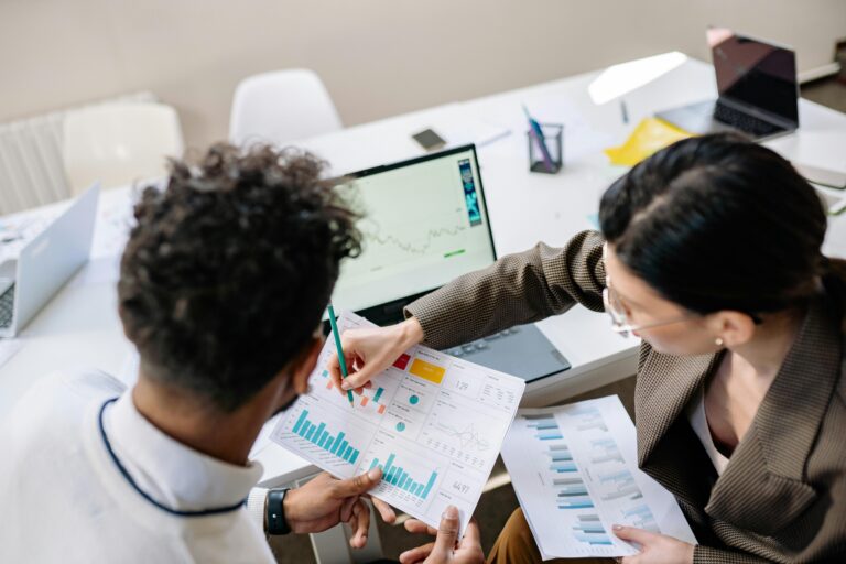 Zwei Personen analysieren Diagramme und HR-Daten am Schreibtisch.