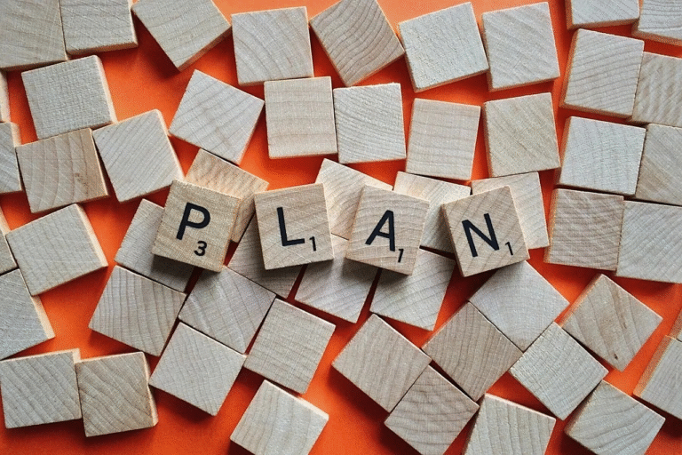 Holzplättchen formen das Wort „PLAN“ – Symbol für strategische Planung und Restrukturierung