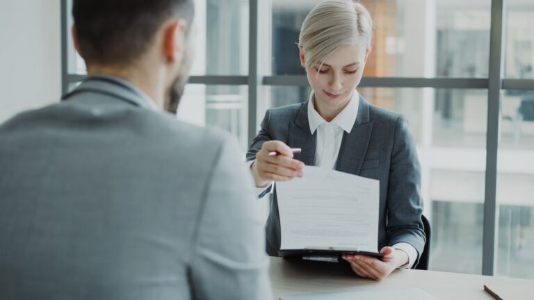 Personalerin überreicht Bewerber einen Vertrag zur Unterschrift im Bewerbungsgespräch